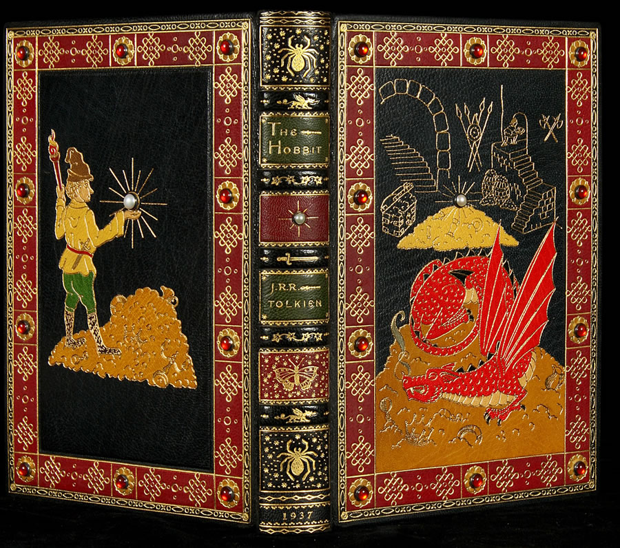 It is gilt tooled, and has on-lays in many colors, with front and rear covers each jeweled with 10 red stones within the borders and a single white jewels within the central designs. A third white jewel adorns the spine. The silk moiré end leaves, gilt-rolled board edges and all gilded page edges, make this Hobbit stunning. 